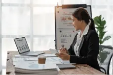 Bookkeeper on SAP HANA 17 A professional working at a desk with a laptop, paperwork, and a coffee cup.