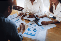 Bookkeeper on SAP HANA 18 Three professionals discussing charts and data during a business meeting.