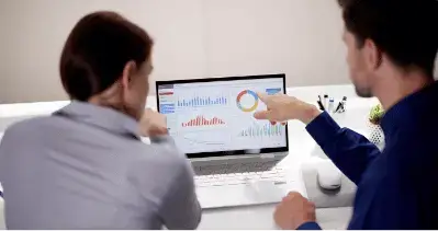 Bookkeeper on SAP HANA 10 Two professionals analyzing graphs and data on a laptop screen.