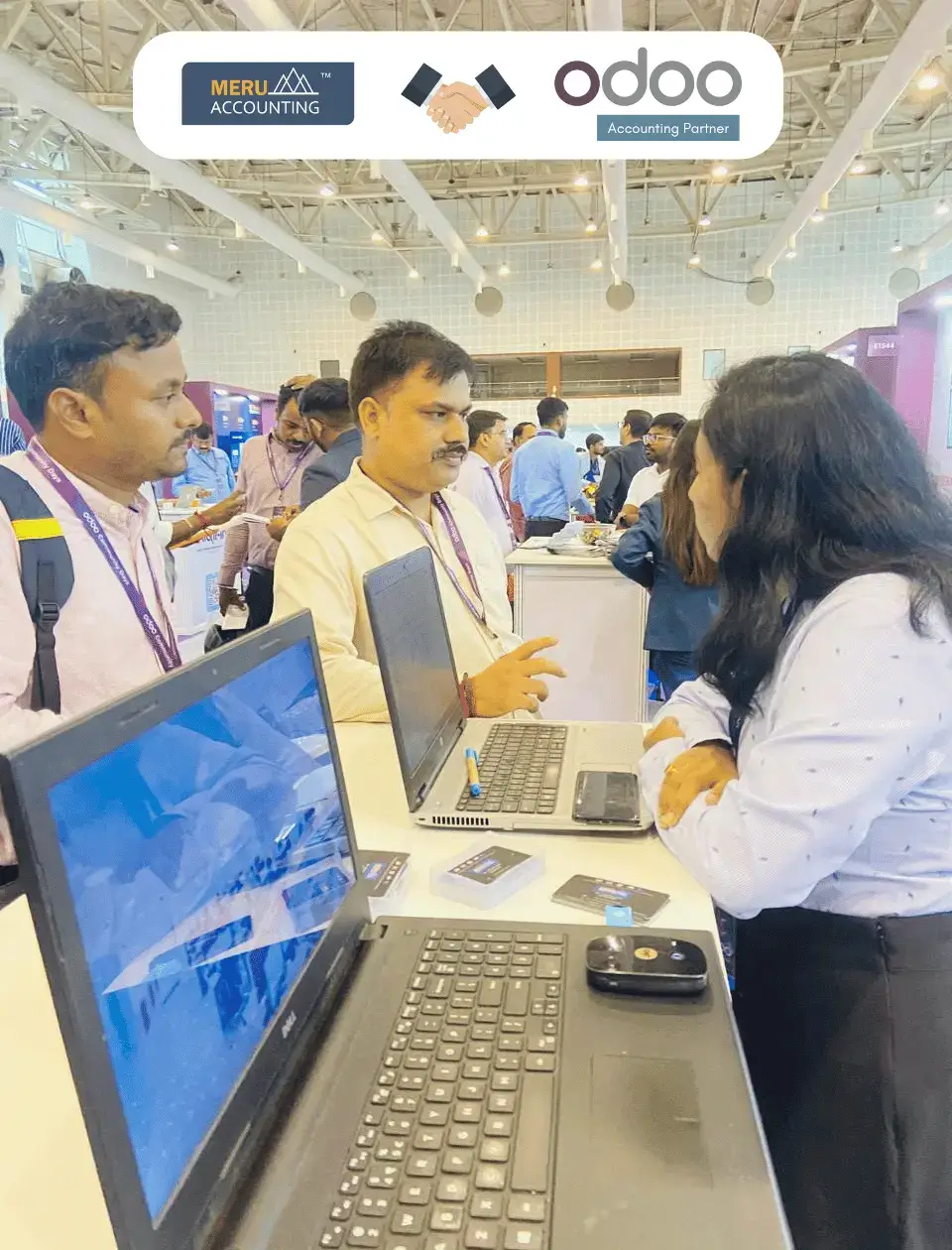 A group of individuals attentively observing laptops during a professional event, engaged in discussions and networking.