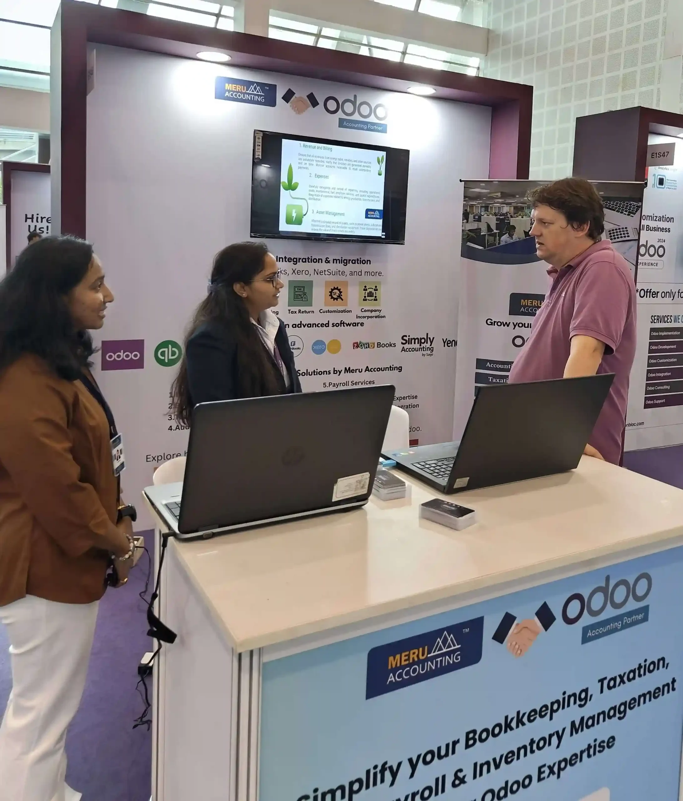 Three individuals engaged at a booth, each using a laptop, showcasing collaboration and technology in a professional setting.